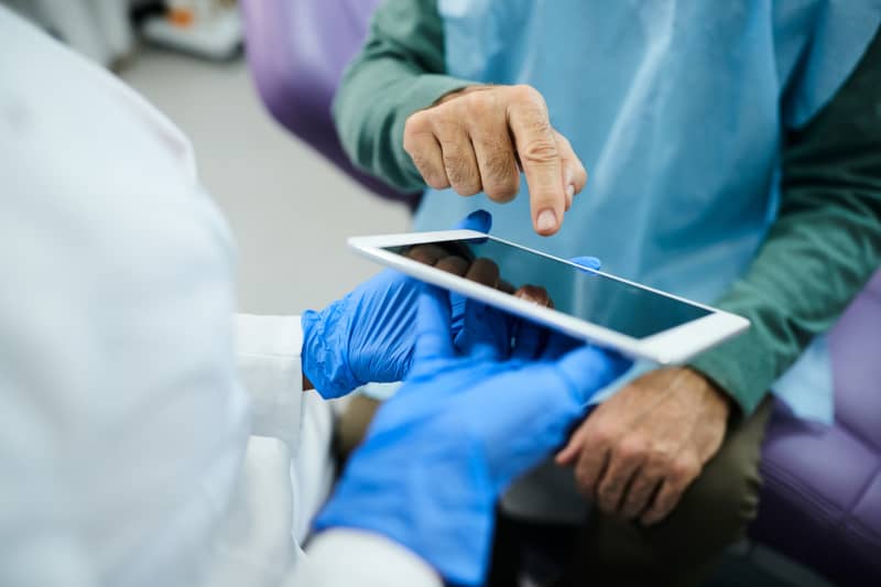 Paciente realizando una firma simple digital con el índice en tableta ofrecida por profesional 